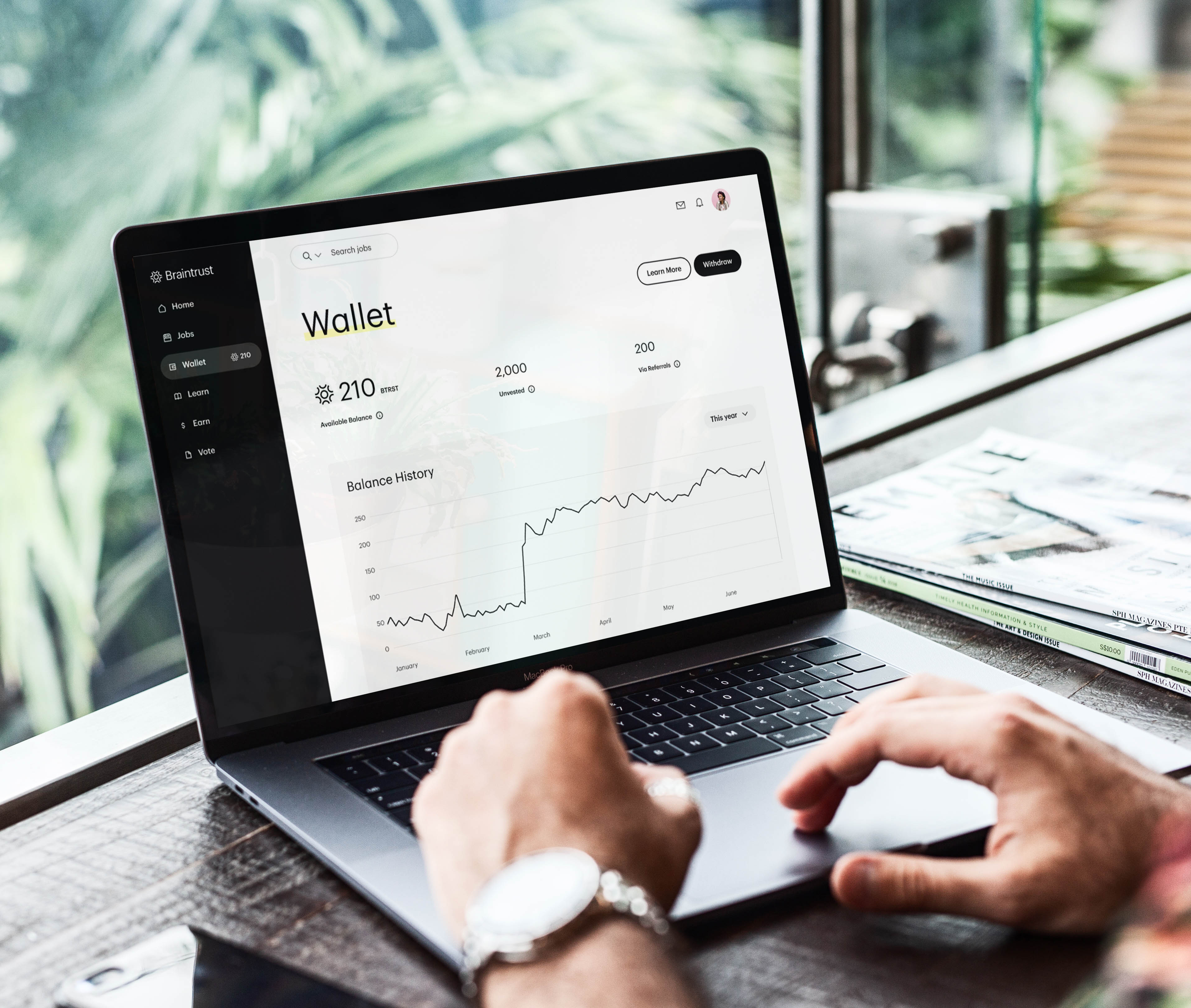Cheerful freelancer using laptop to check crypto wallet with Base network logos in the background, illustrating earning USDC on Base.
