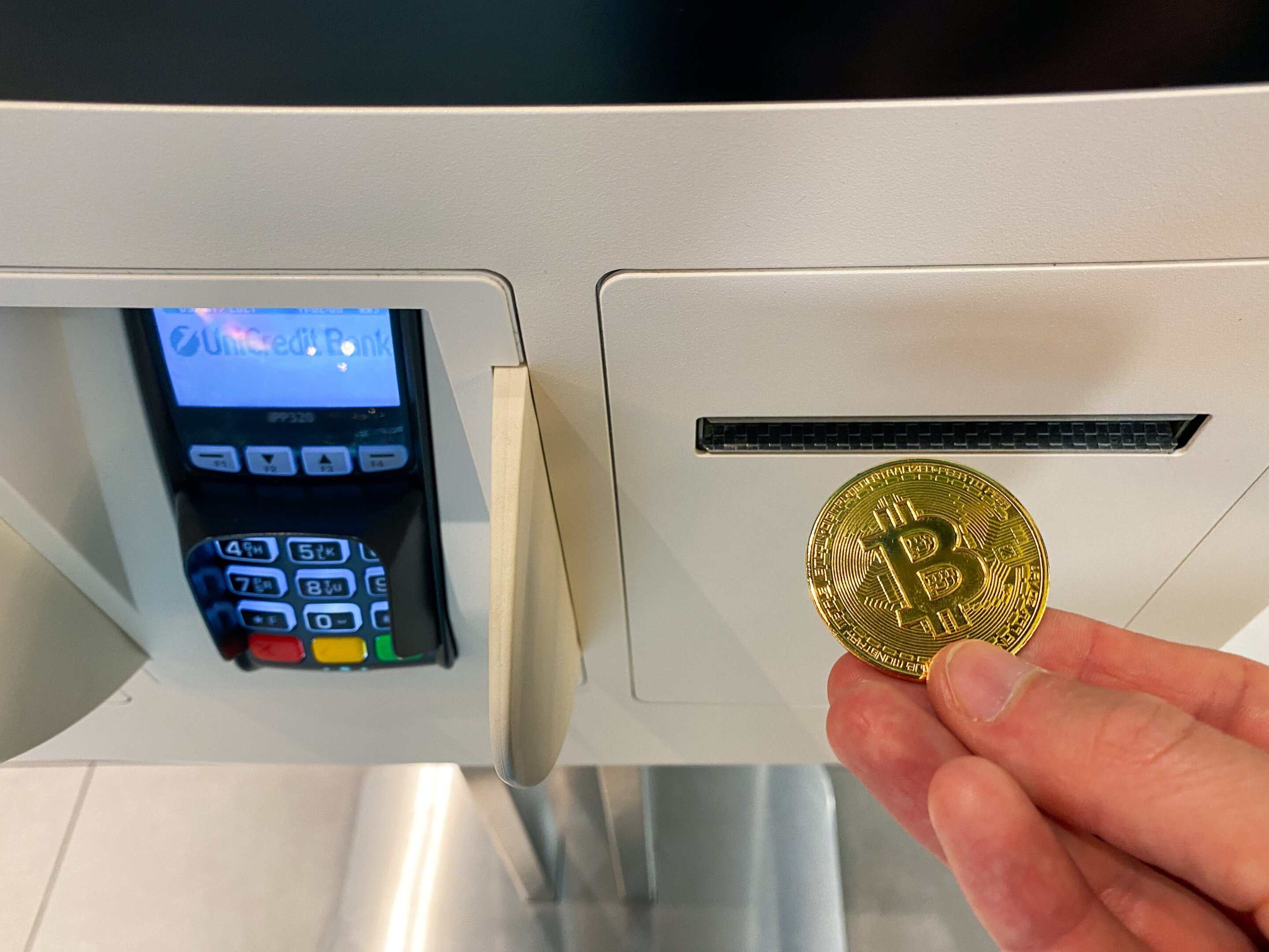 Person using a hardware crypto wallet next to a modern crypto ATM in Arizona, illustrating secure wallet practices and new state regulations against scams in 2025.