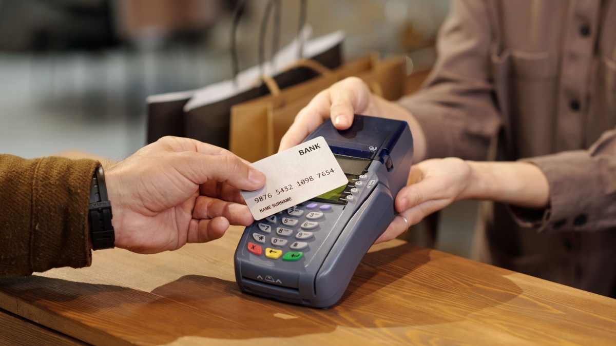 Person tapping a stablecoin card at a contactless payment terminal, illustrating seamless crypto payments with DeFi wallet integration