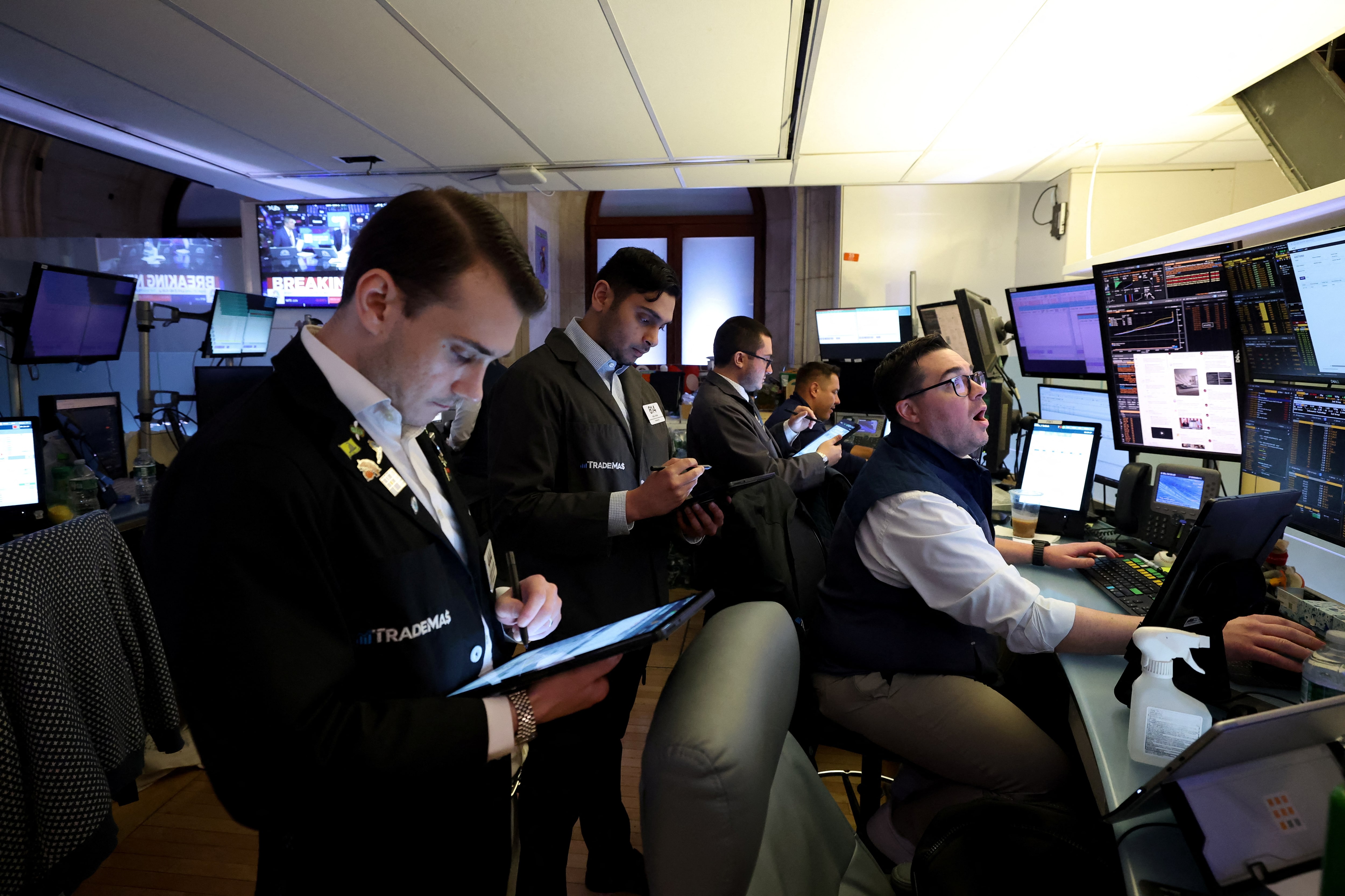 Wall Street traders monitoring crypto ETF prices on large digital monitors in a bustling trading floor environment, reflecting the impact of SEC's new generic listing standards in 2024.
