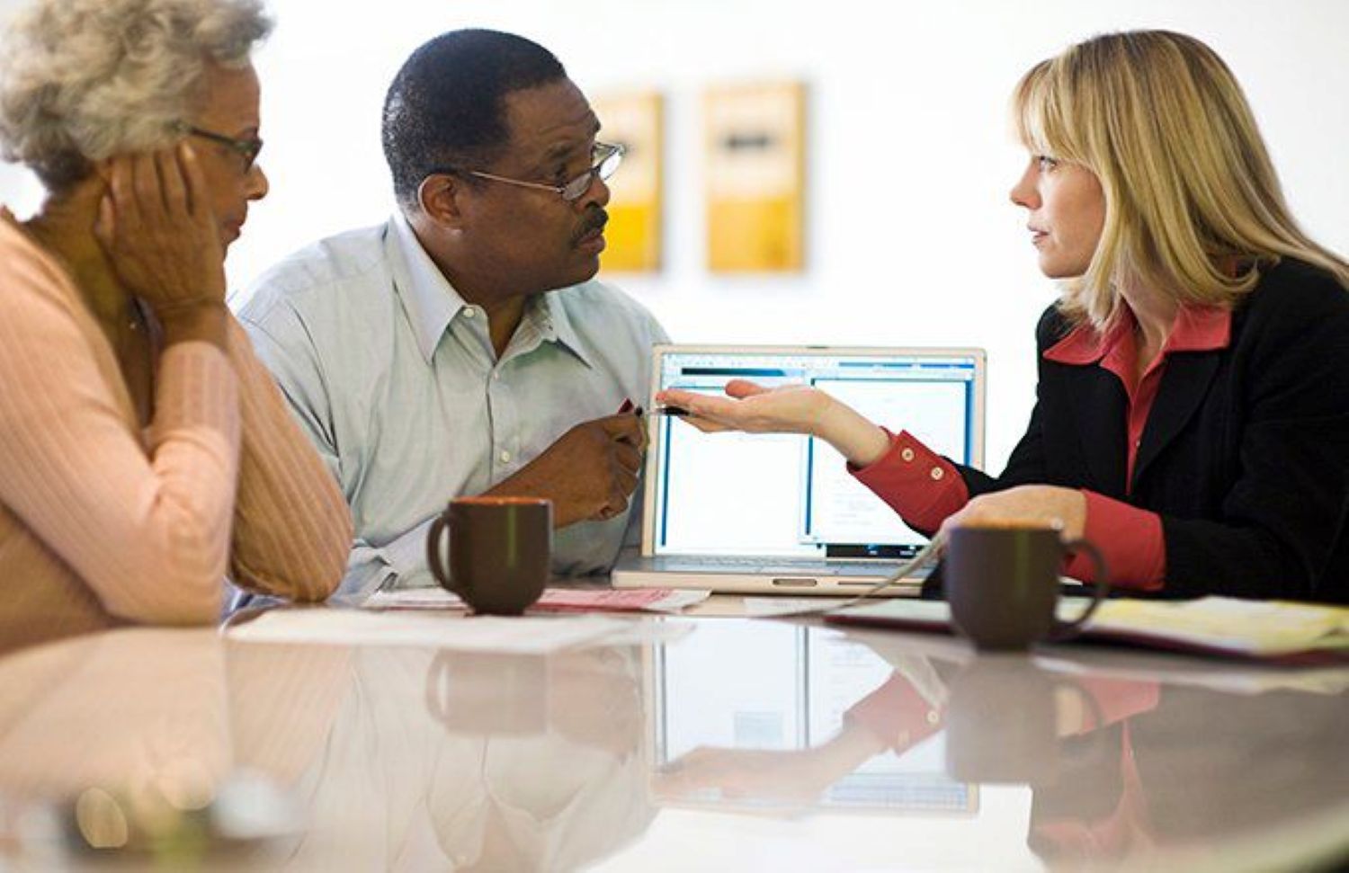 Financial advisor and retiree discussing cryptocurrency investments for 401k retirement planning, reviewing digital crypto charts together in a professional office setting.