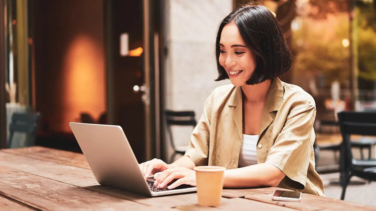 Remote worker checking USDC salary on mobile wallet at sunny café, representing global crypto payroll in 2025