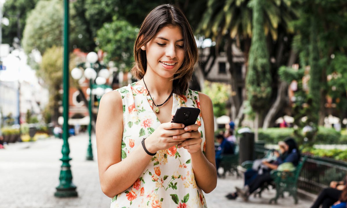 Young woman in Mexico City paying at a street food vendor with her phone using a stablecoin-powered Visa card