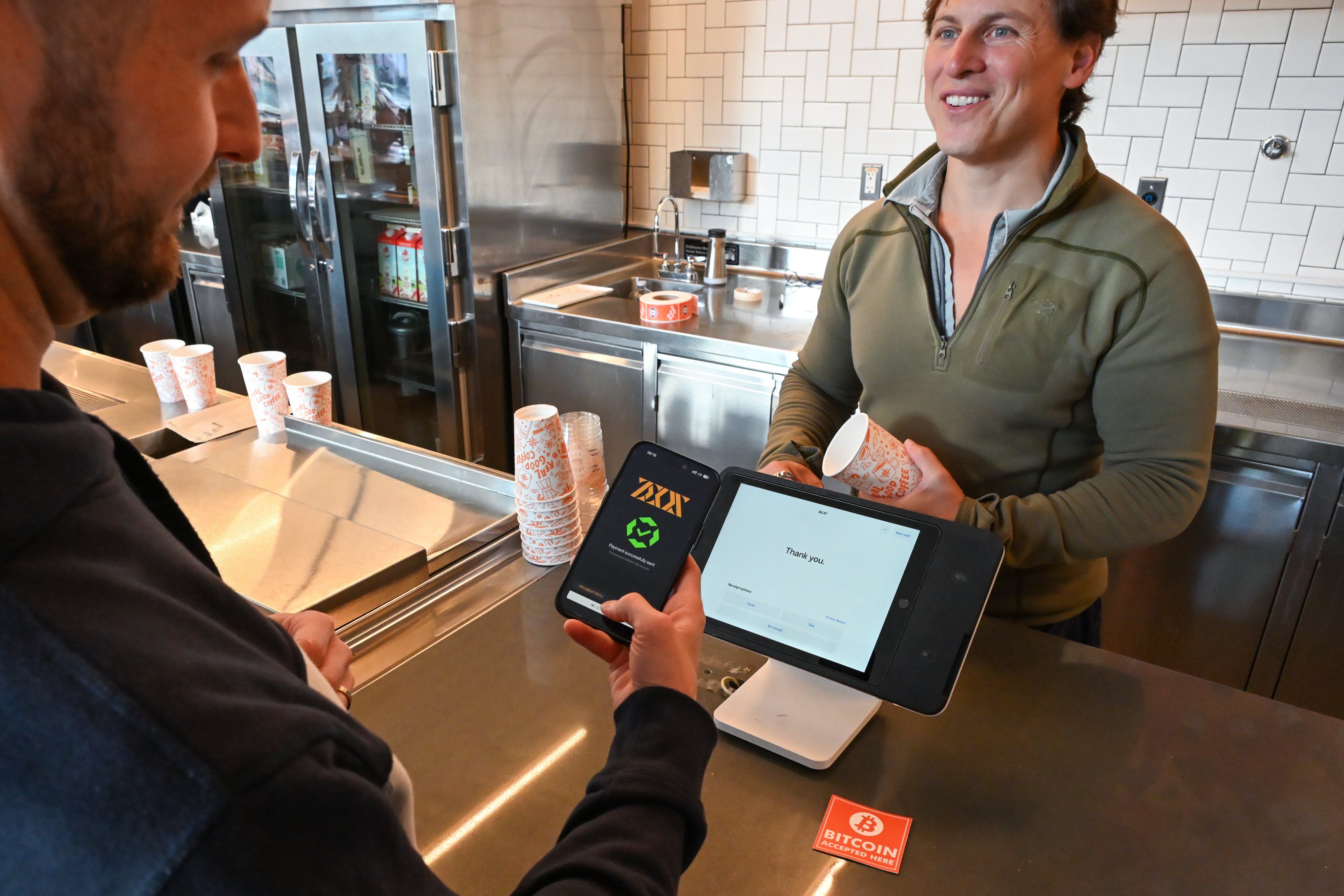 Busy retail shop counter with NFC-enabled USDC POS terminal accepting Lightning Network payment tap for offline crypto transactions in 2026
