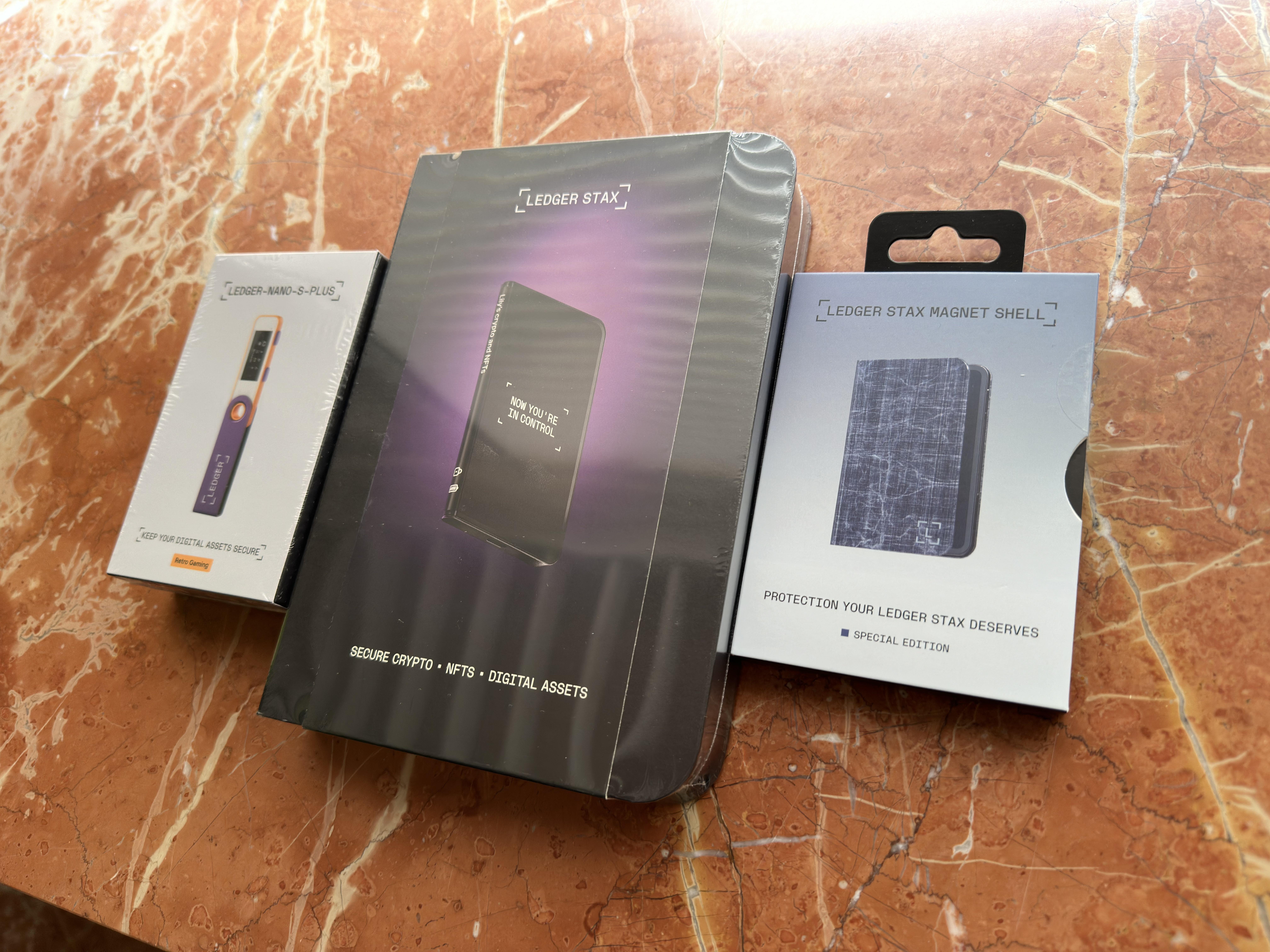 Close-up of Ledger Stax and Trezor Safe 5 hardware wallets side by side on a modern desk, showcasing their latest 2025 designs and touchscreen features
