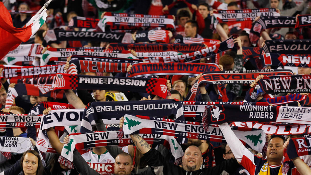 Soccer fans in stadium holding up team scarves with logos, showing support and excitement