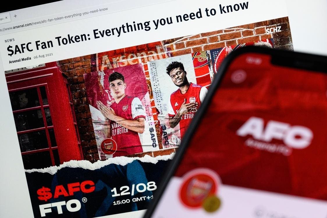 Soccer fans in a stadium holding smartphones displaying a fan token app, showcasing digital engagement with their favorite teams on blockchain platforms.