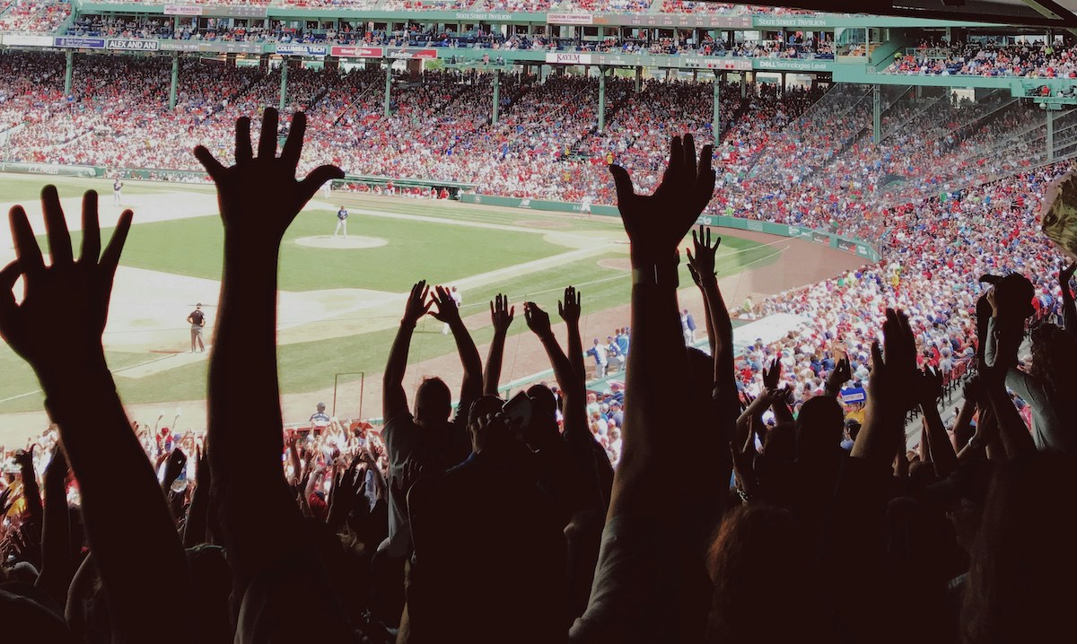 Fans waving digital passes at the entrance of a newly upgraded football stadium, showcasing fan token-powered access and modern stadium technology in 2025.