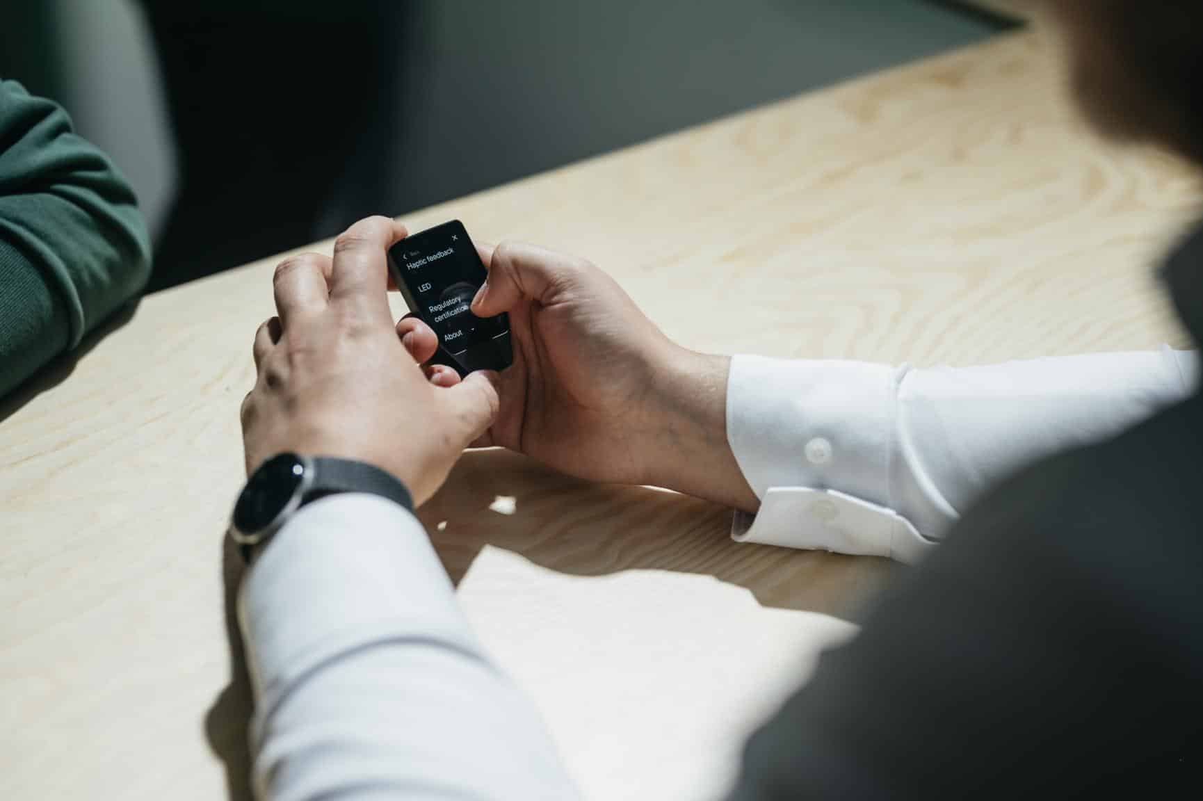 Trezor Safe 7 unboxing showing aluminum hardware wallet, USB-C cable, backup cards, and accessories on table