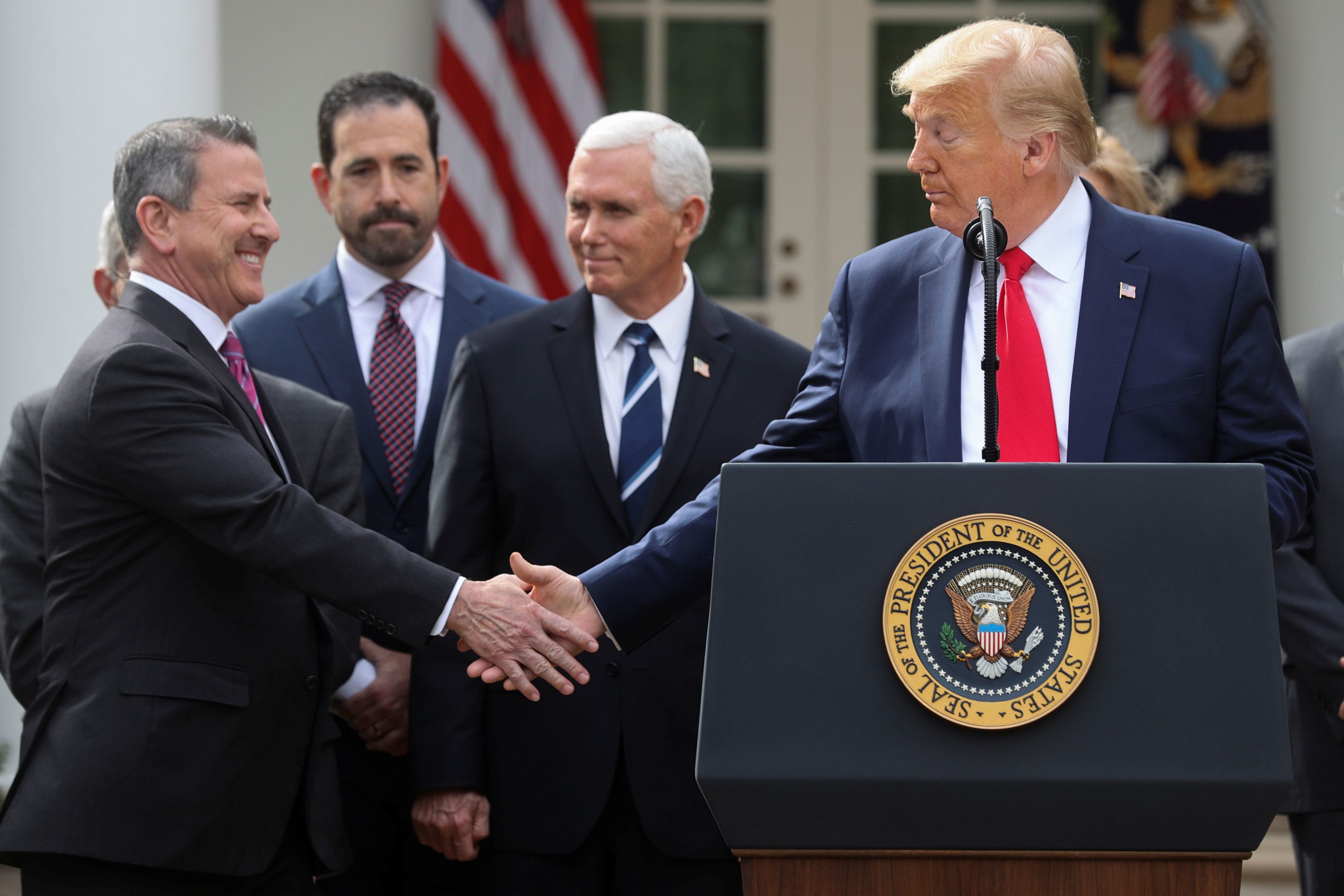 Donald Trump and Crypto.com executives shaking hands at a press conference announcing a $6.4 billion cryptocurrency partnership in 2025