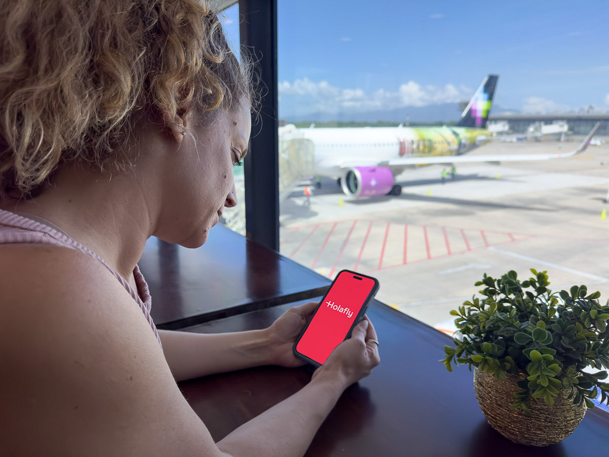 Vibrant digital nomad booking flight with USDC stablecoin on smartphone against modern airport backdrop, blockchain travel payments 2026