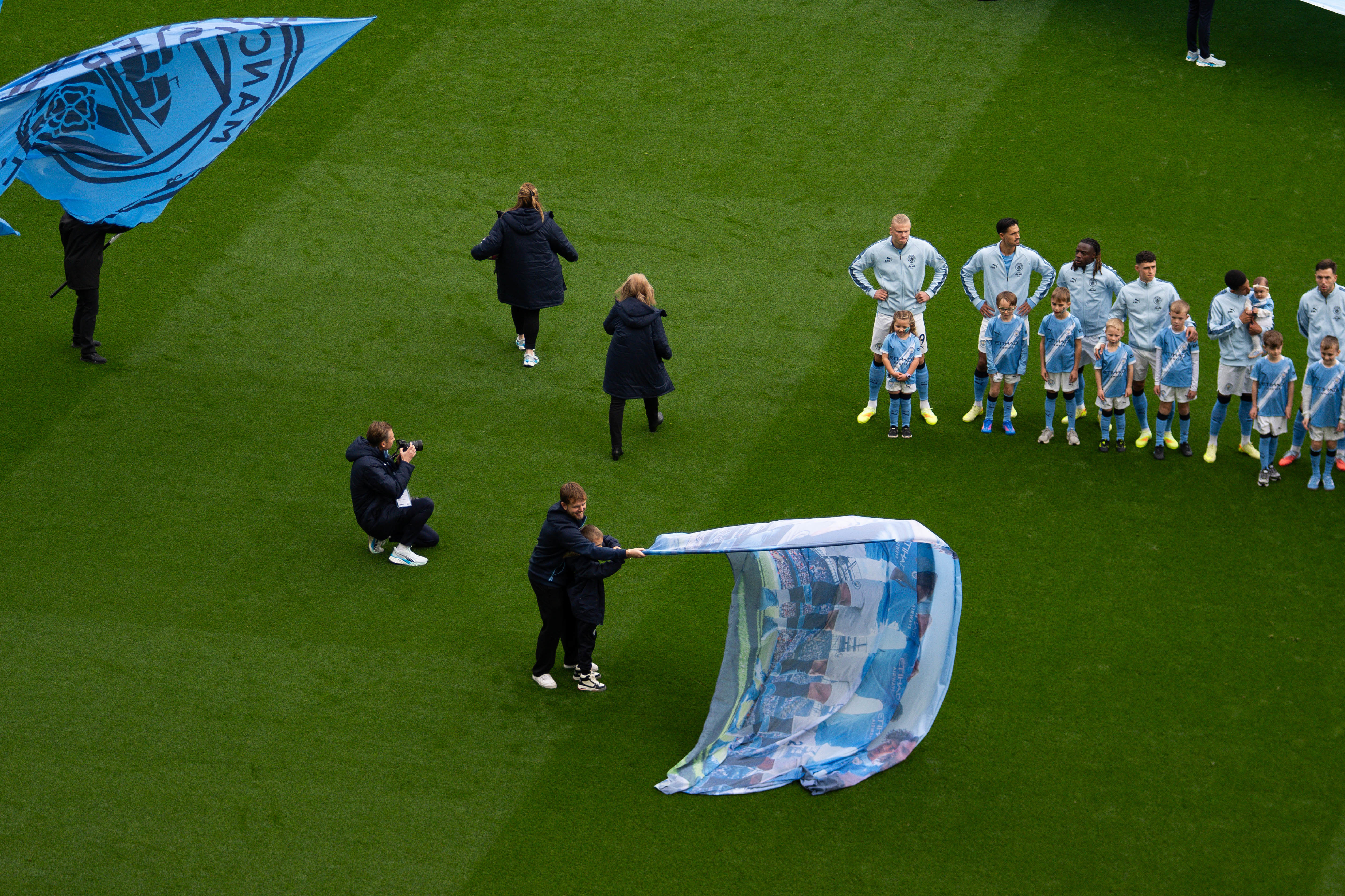 Vibrant photo of excited Manchester City fans at Etihad Stadium using Socios app for $CITY Fan Token polls on matchday decisions, showcasing fan engagement perks